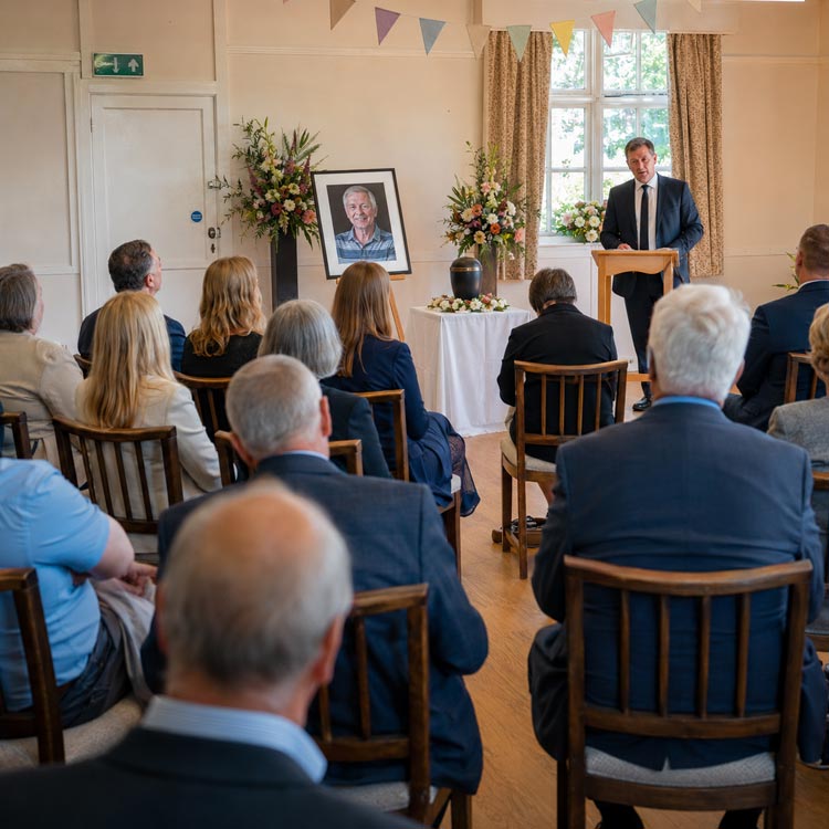 Cremation with a memorial service in Borough Green showing family and friends gathered with ashes, flowers and photographs after a private cremation.